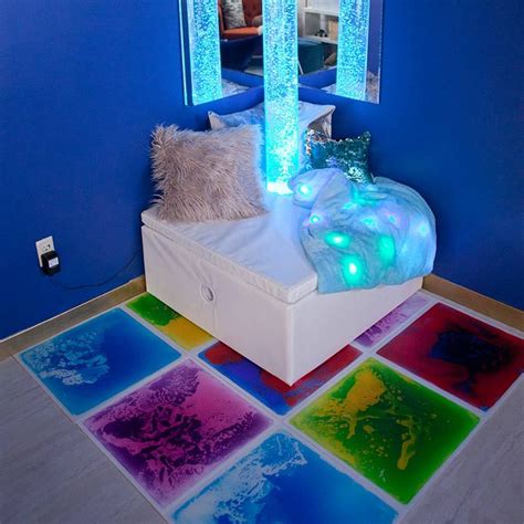 a room with blue walls and flooring has colorful tiles on the floor that are lit up