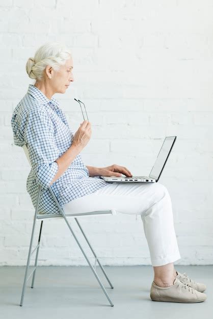 Free Photo | Senior woman sitting on chair using laptop