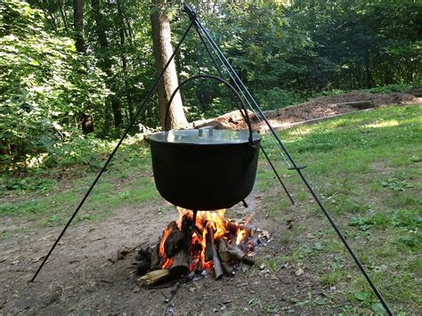 A large metal pot with a lid and handle, used for cooking over an open ...