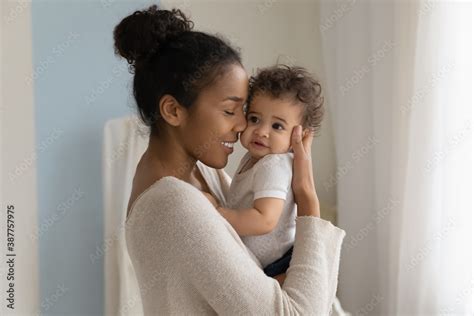 Happy young African American mom hold in hands hug cute little ethnic ...