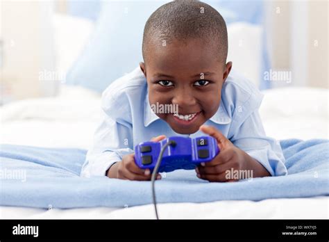 Smiling little boy playing video game lying on a bed Stock Photo - Alamy