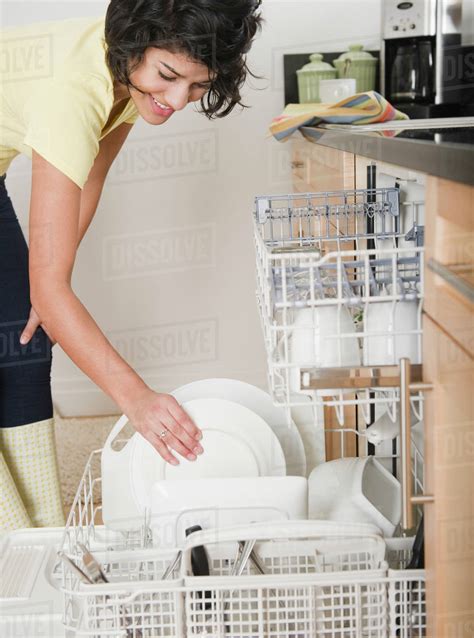 Hispanic woman putting dishes in dishwasher - Stock Photo - Dissolve