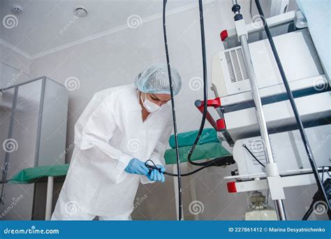 A Young Female Endoscopist in a White Protective Suit, Cap and Gloves Prepares the Equipment for ...