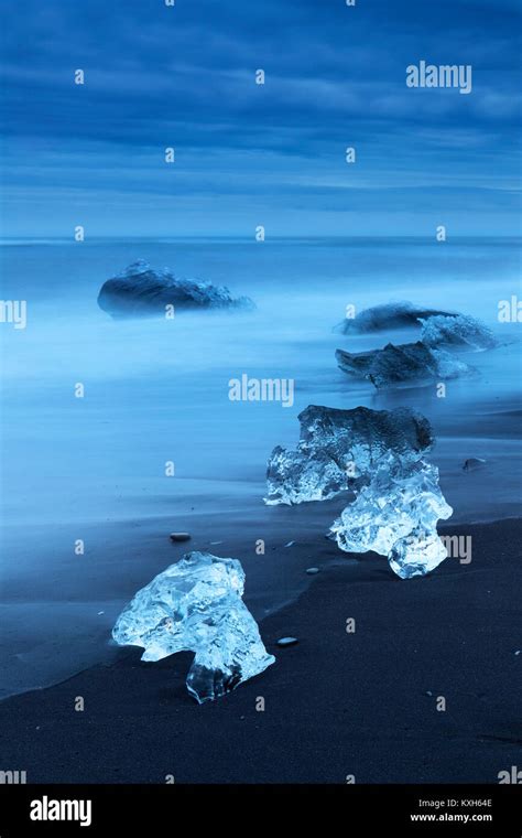 Diamond Beach, pieces of ice on the beach with icebergs in the background Stock Photo - Alamy