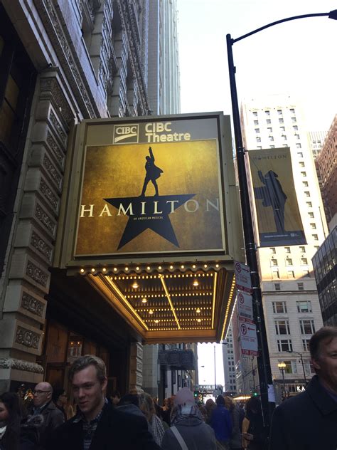 people walking down the street in front of a theater sign that says'hamilton