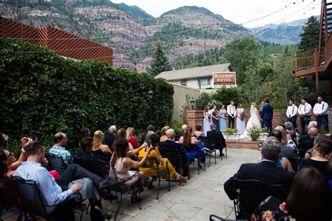 a group of people that are standing in front of some bushes and trees with mountains in the ...