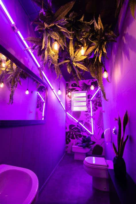 a bathroom with purple lighting and plants hanging from the ceiling