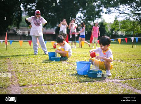 Children compete in fill-the-bottle game during their kindergarten ...