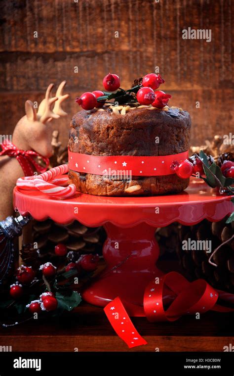 Festive Christmas small rich fruit cake on a red cake stand with reindeer and ornaments on a ...