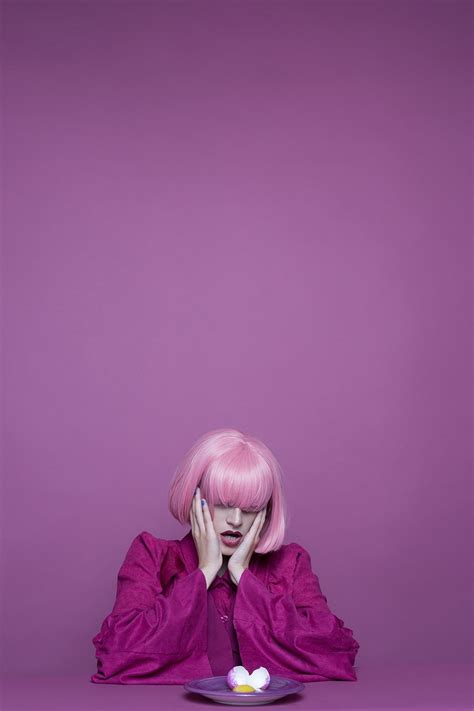 a woman with pink hair sitting in front of a plate