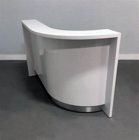 a curved white counter sitting on top of a gray floor