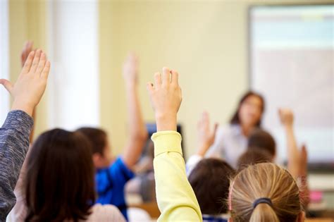 group of school kids raising hands in classroom | National Association of Certified Mediators