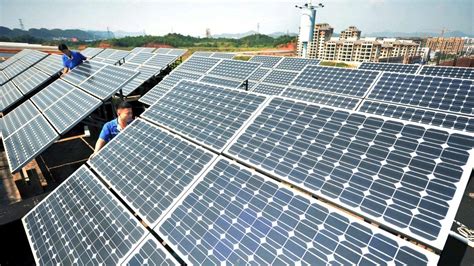 Workers install solar panels on the rooftop of a company in Shangrao, Jiangxi province, China ...