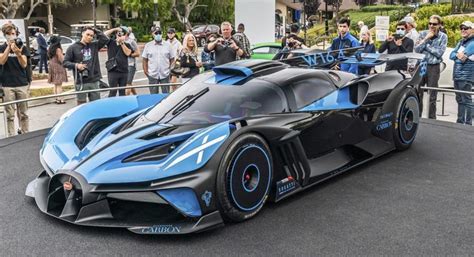 a blue and black sports car parked in front of a building with people standing around