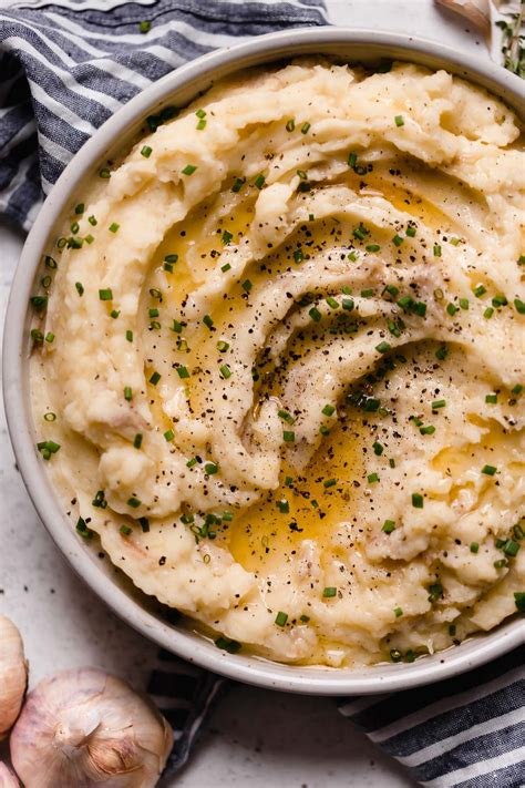 mashed potatoes in a white bowl with parsley on top and garlic ...