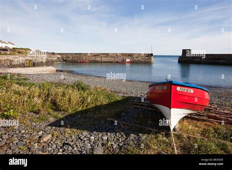 Craster, Northumberland, England, UK. Red boat on shore by harbour in ...