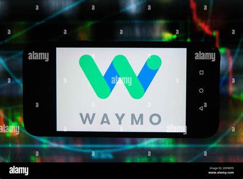 In this photo illustration a Waymo logo is displayed on a smartphone with stock market graphics ...