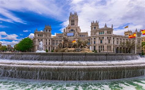 a fountain in front of a large building with flags on the roof and water cascading