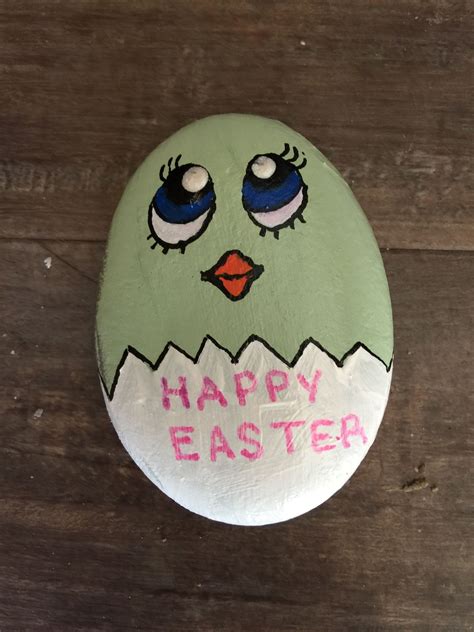an egg with eyes and the words happy easter painted on it sitting on a wooden surface