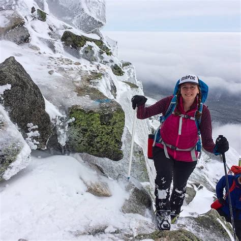 a woman hiking up the side of a snow covered mountain