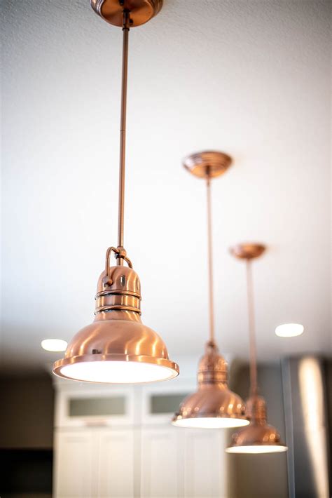 Copper metal hanging light fixtures over a huge kitchen island with matching copper… | Kitchen ...