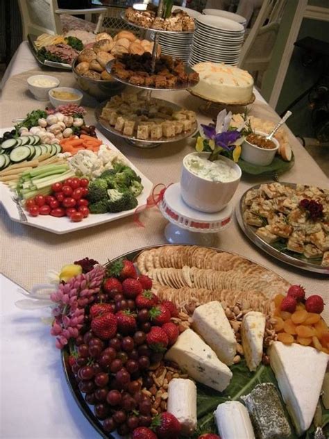 an assortment of cheeses, crackers and fruits on a table with other foods