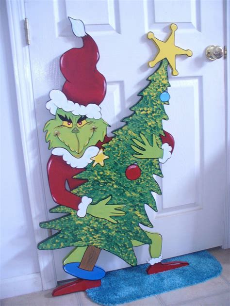 the grinch is standing in front of the door with a christmas tree on it