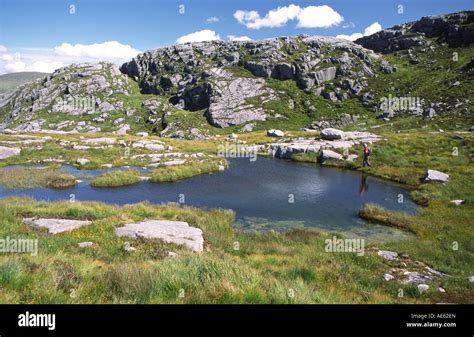 Hill walking Scotland Galloway Hills hill walker walkng beside a lochan Galloway Forest Park UK ...