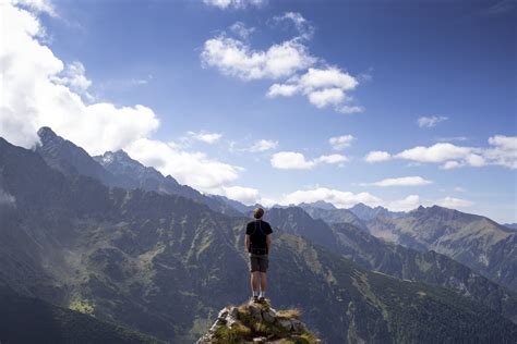 Man in black t-shirt standing on mountain cliff under blue sky HD wallpaper | Wallpaper Flare