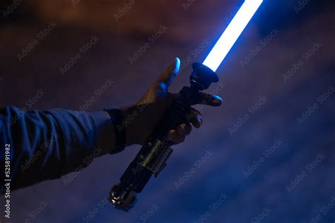 Man holding Lightsaber with blue emitted blade Stock Photo | Adobe Stock