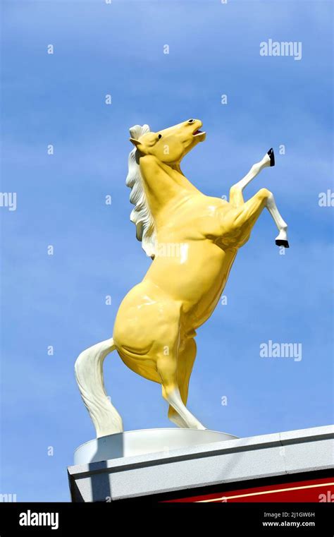 Statue of a wild stallion rearing its legs into the air, is sillouetted against a blue sky in ...