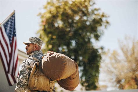 Courageous young soldier walking towards his house with his luggage ...