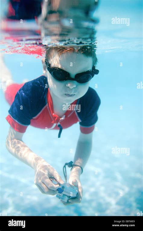 little boy wearing swimming goggles diving with an underwater camera in ...