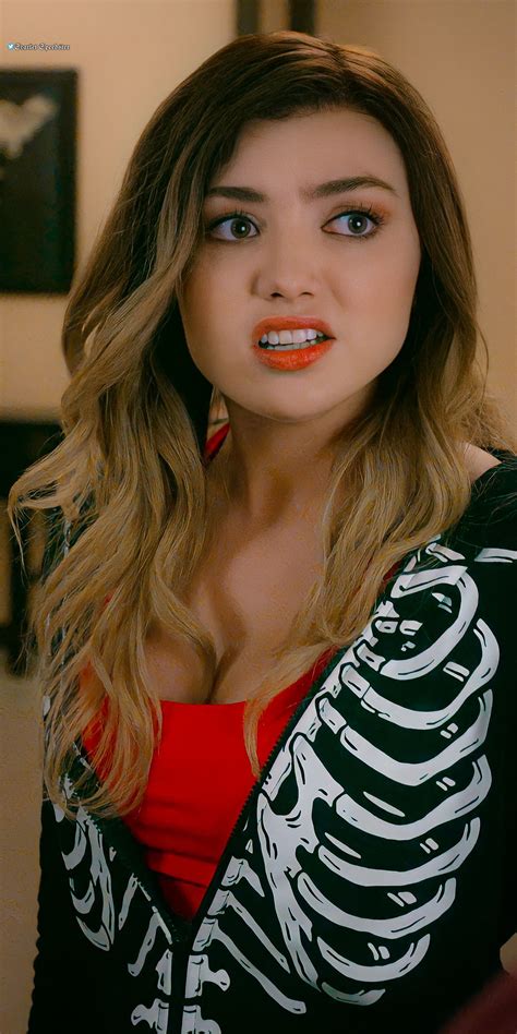 a woman with long hair and orange lipstick looks at the camera while wearing a skeleton shirt