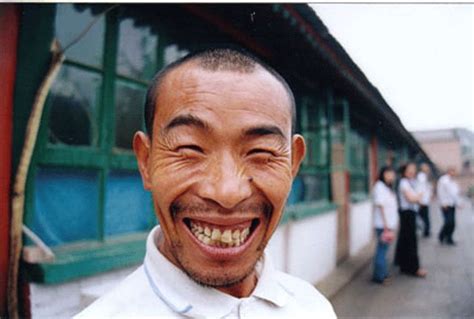 a smiling man with his mouth open in front of a group of people on the sidewalk