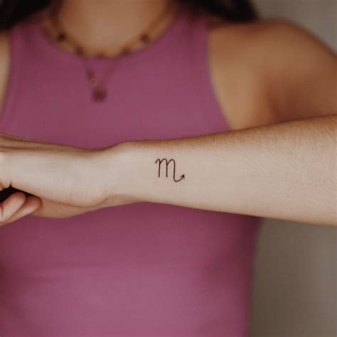 Minimalist Scorpio zodiac symbol tattoo on the wrist.