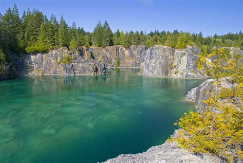 a lake surrounded by trees and rocks in the middle of a forested area ...