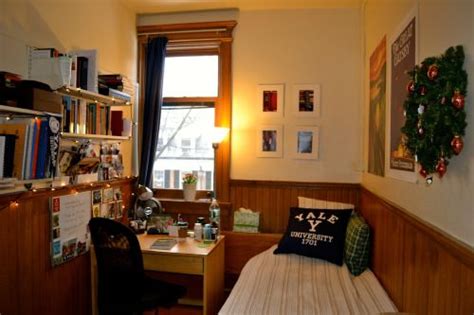 a bedroom with a bed, desk and bookshelf in the corner next to a window