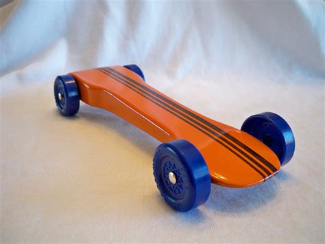 an orange skateboard sitting on top of a white sheet with blue wheels and spokes