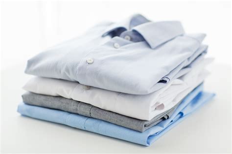 close up of ironed and folded shirts on table - Comet Cleaners