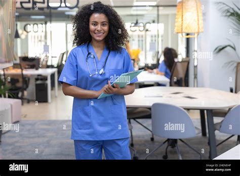 Beautiful african american nurse wearing blue uniform smiling and looking at camera Stock Photo ...