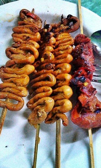 several skewered sausages and other food items on a white plate with forks