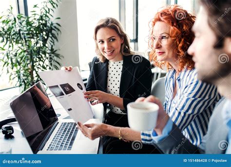 A Group of Young Business People with Laptop Sitting in an Office, Talking. Stock Photo - Image ...