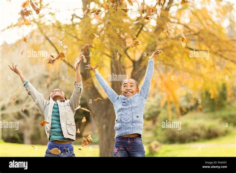 Portrait of young children throwing leaves around Stock Photo - Alamy