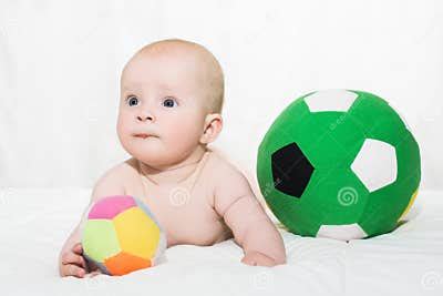 Baby Boy or Girl Lying Down on His Belly and Playing with Soccer Balls Stock Photo - Image of ...