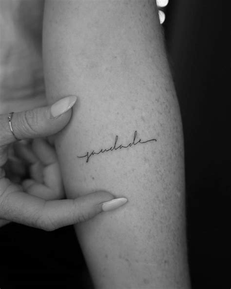 Tattoo of the word "saudade" handwritten on the inner