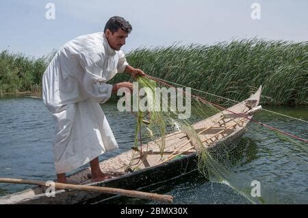 A Marsh Arab fisherman balances on his traditional boat (Mashoof ...