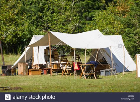 White canvas tents and awning with wood camp furniture and supplies ...