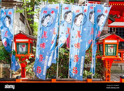 Yasaka shrine at Kyoto. Two wooden orange pedestal lanterns with fluttering blue banners with ...