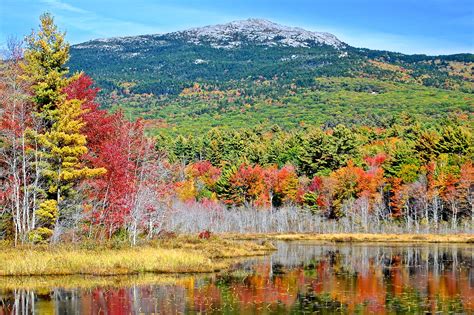 the mountains are covered in autumn foliage and trees with red, orange, yellow, and green leaves